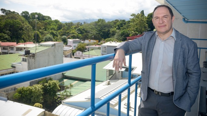 Tomás Martínez Baldares posa para la foto en el balcón del último piso del edificio Rafles del Campus TEC San José. Al fondo se aprecian los techos de las casas de Barrio Amón y los árboles del corredor biológico del Río Torres.