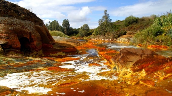 La imagen es una fotografía del río tinto. El objetivo principal de la fotografía es mostrar el color rojizo del agua. 