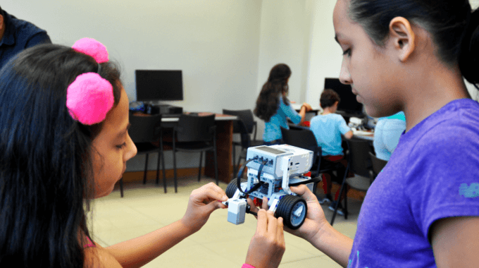 dos niñas con modelo robótico entre sus manos