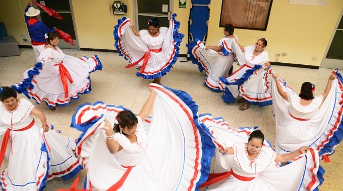 Un grupo de señoras baila con el vestido típico, de color blanco con ribetes azul y rojo.