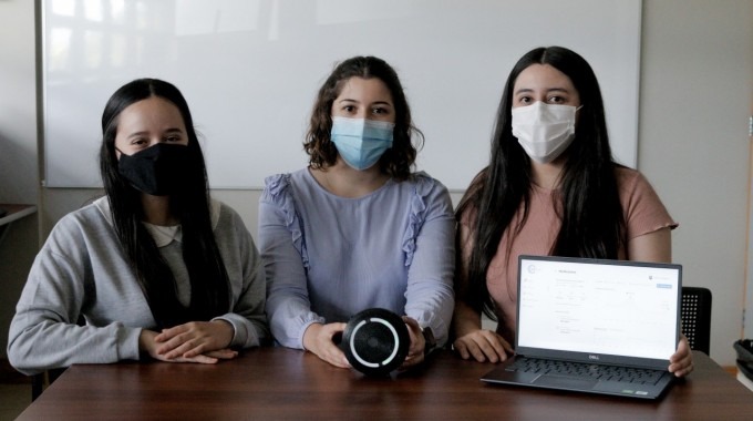 Imagen con tres estudiantes mostrando el dispositivo que mide el dióxido de carbono (CO2) en espacios cerrados