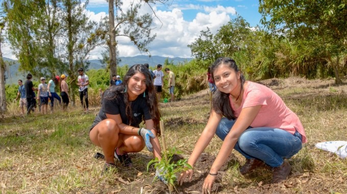 dos mujeres jóvenes sembrando un árbol