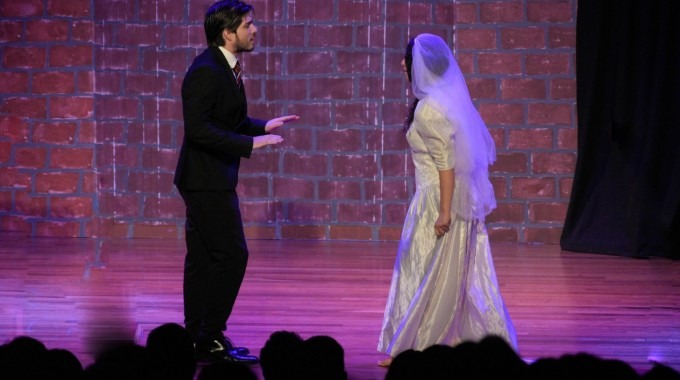 Un hombre y una mujer con ropa de boda en el escenario.