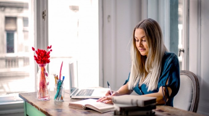 Mujer trabajando en computadora portátil en escritorio dentro de una casa.