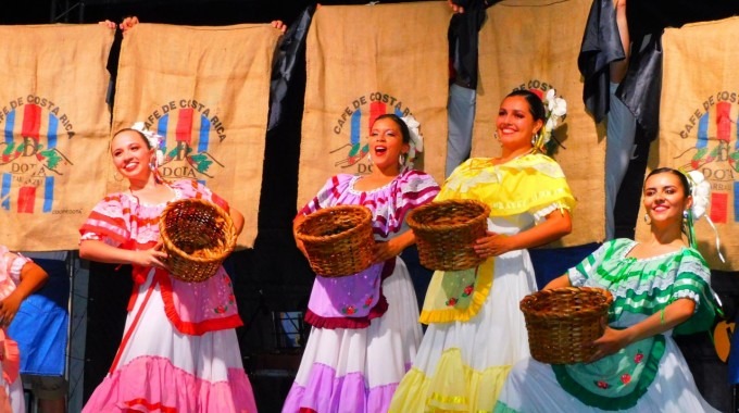 4 bailarinas de Tierra y Cosecha vestidas con traje típico sostienen, cada una, una canasta de recolectar café. 
