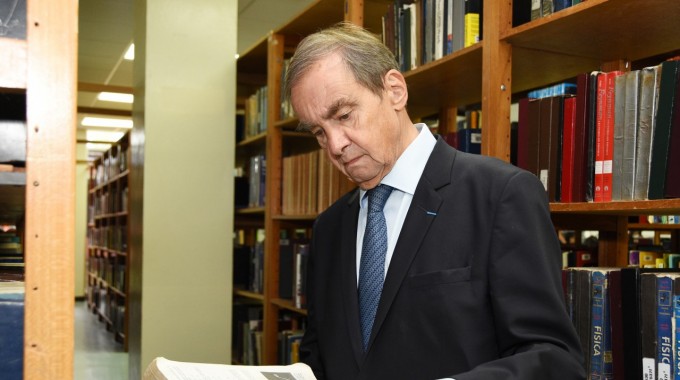 Hombre leyendo observando un libro.