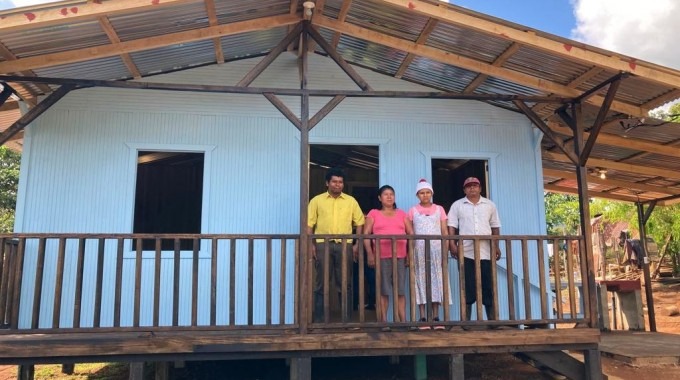 La casa es de madera y de color celeste, en el correpor está la familia beneficiada.