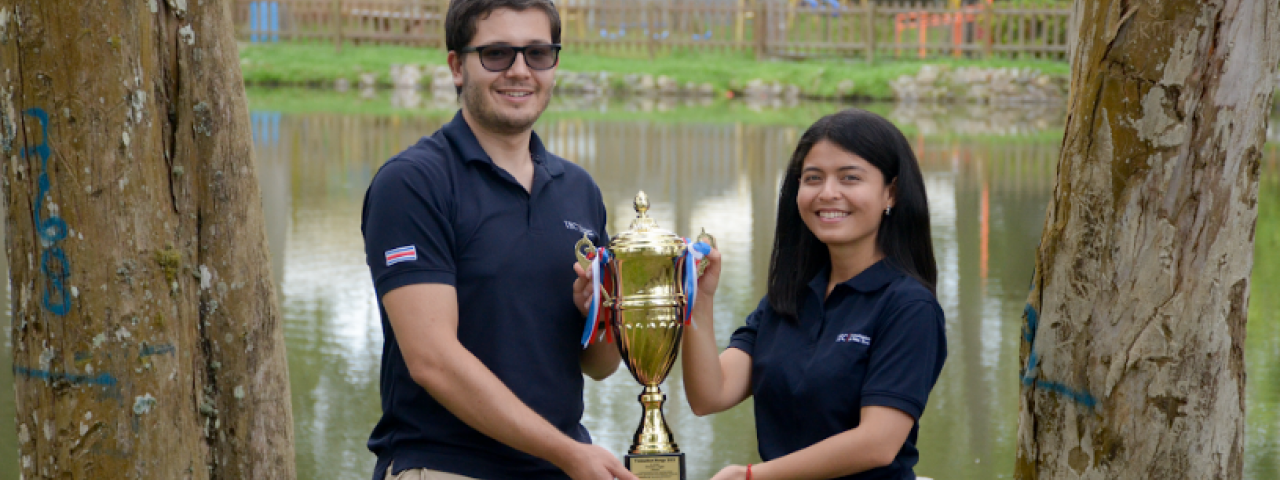 Imagen de dos estudiantes sosteniendo el trofeo