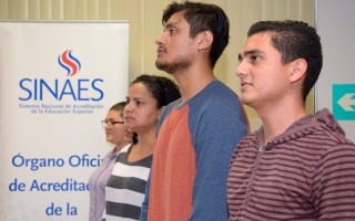 Estudiantes posando a la par de banner con logo de SINAES. 