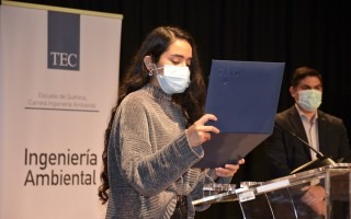 Estudiante sostiene y lee el certificado de acreditación.