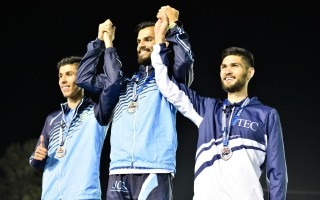 Imagen de tres muchachos tomados de las manos recibiendo la medalla.