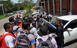 Jóvenes alrededor de un auto eléctrico.