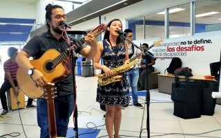 Un estudiante con guitarra y una estudiante cantando.