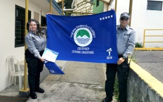 Dos guardas muestran la bandera azul del galardón.