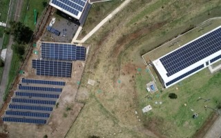 Vista aérea de los paneles solares, tanto en piso como en el tejado de un edificio.