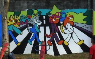 Mural de Munguía en un parque infantil que hace una parodia con gatos de la imagen icónica de la banda The Beatles pasando por un cruce peatonal.
