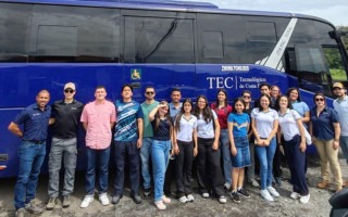 Imagen de varias personas junto a un autobus.  Las personas van rumbo a Parismina.