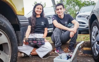 Los jóvenes con la computadora y el dispositivo, realizando pruebas. 