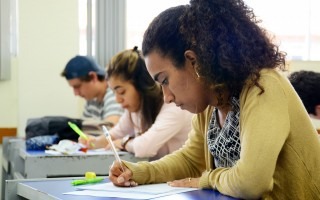 Imagen de una estudiante sentada en su pupitre dentro del aula.