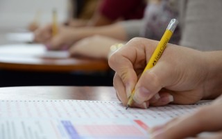 Imagen de una estudiante realizando el examen de admisión. En la fotografía se detalla la mano  con el lápiz.