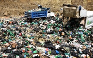 Imagen de un relleno sanitario con dos camiones de basura