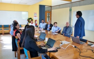 El ingeniero expone mientras las demás personas ponen atención, sentadas en la mesa.