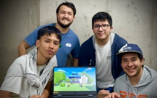 Jóvenes posan mostrando en una computadora el videjuego desarrollado. 