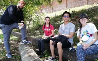 Cuatro estudiantes toman una merienda bajo la sombra de un árbol.