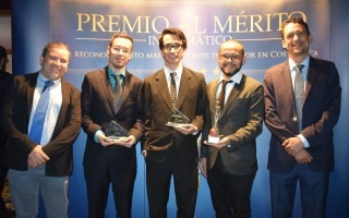 Los cinco ingenieros posan frente a un rótulo de Premio al Mérito Informático.