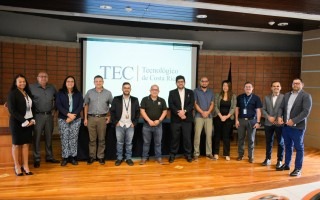 Hombres y mujeres posando en el auditorio, con el logo del TEC de fondo. 