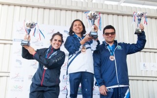 tres personas en un podio alzando los trofeos