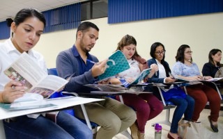 Imagen de varias personas sentadas viendo libros.