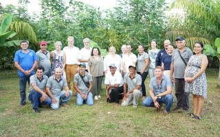 Un grupo de personas posan frente a la plantación.