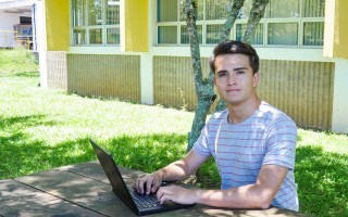 Imagen de un estudiante sentado con la computadora.