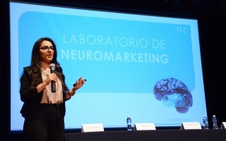 Mujer exponiendo el tema de neuromarketing a un grupo de empresarios.