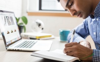 estudiante escribiendo junto a computadora