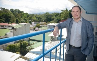 Tomás Martínez Baldares posa para la foto en el balcón del último piso del edificio Rafles del Campus TEC San José. Al fondo se aprecian los techos de las casas de Barrio Amón y los árboles del corredor biológico del Río Torres.