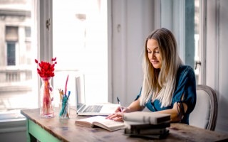 Mujer trabajando en computadora portátil en escritorio dentro de una casa.