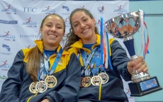 Dos jugadoras posan con el trofeo y las medallas.