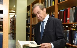 Hombre leyendo observando un libro.