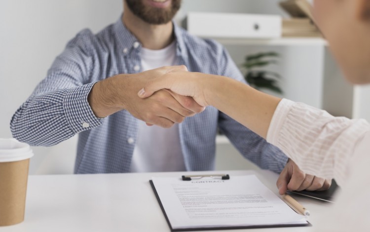 La imagen muestra a dos personas dándose la mano. Se busca ejemplificar el enlace con la industria