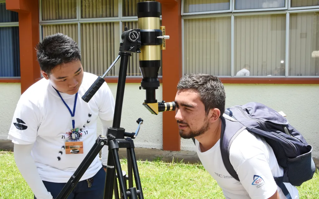 dos personas observan a través de un telescopio