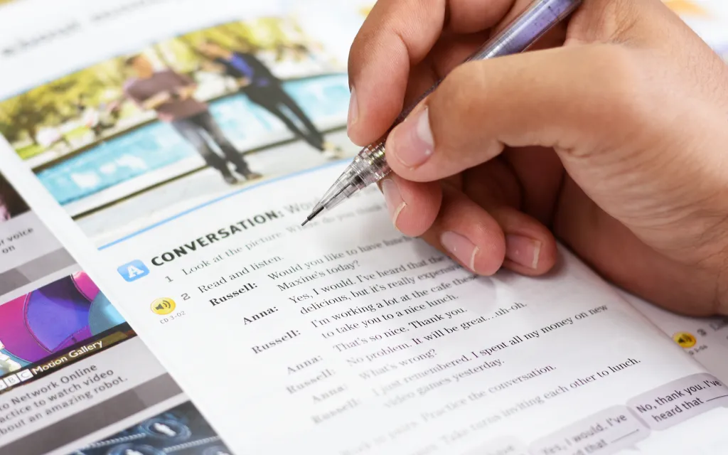 Persona escribiendo en un libro en inglés.