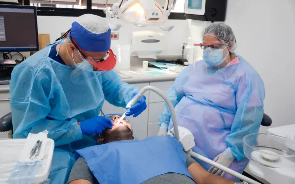Odontólogo y su asistente atendiendo a un estudiante