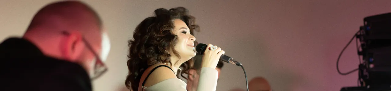Mujer con un micrófono cantando en un estudio oscuro