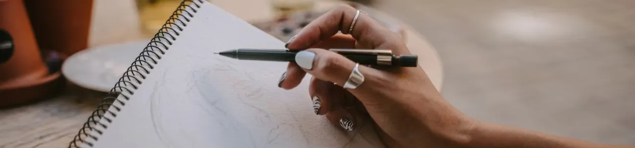 Enfoque de una mano con un lápiz y un cuaderno de bocetos