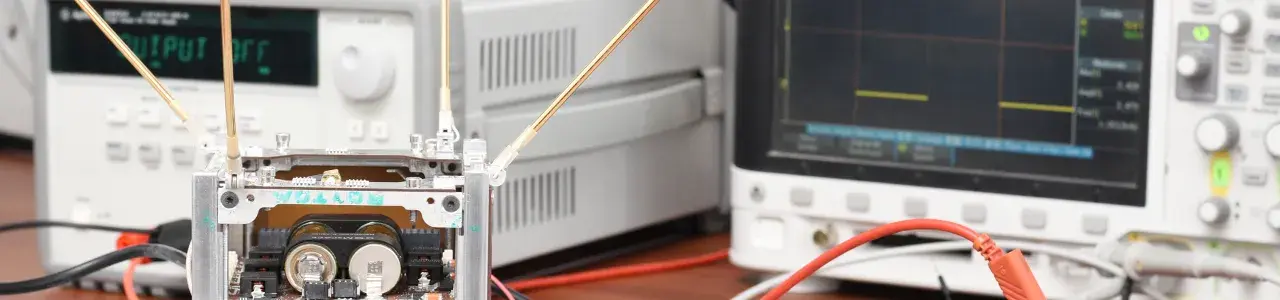 El satélite en una mesa, frente a equipo de medición. 