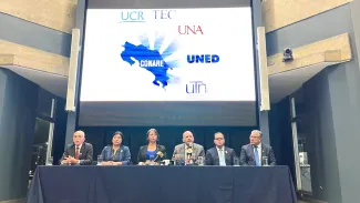 Rectores y rectora con una proyección de los logos de las universidades