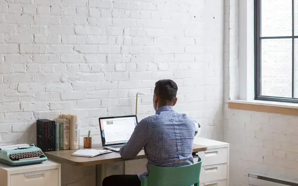 Hombre trabajando con computadora desde su casa.