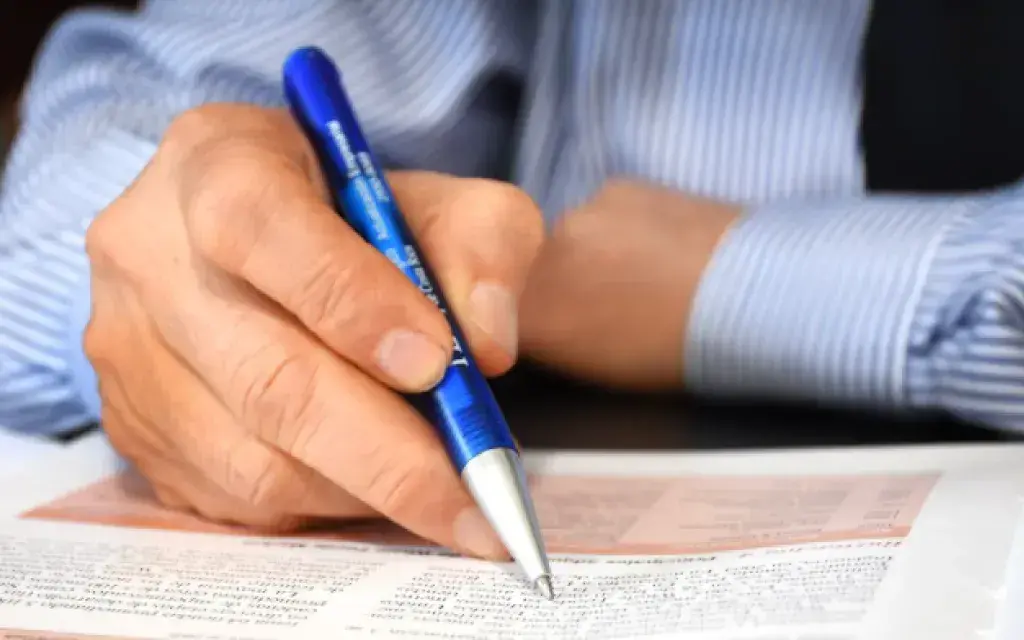 persona escribiendo en una hoja con un lapicero